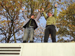 Momente von Veranstaltungen und Aktionen von Einsweiter. Zwei Menschen auf dem Dach vom Einsweiter-Bus. 