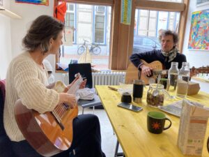 Bild vom offenen Treff im Einsweiter-Büro. zwei Teilnehmer spielen Gitarre und singen. 