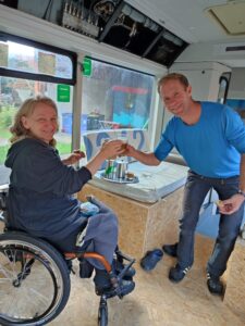 Rollstuhlgerechter Umbau von Bus "Bernhard". Denise und ein Helfer stoßen auf den erfolgreichen Umbau an. 